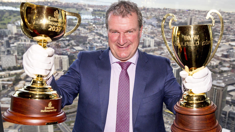 Darren Weir, pictured here with the 2017 Melbourne Cup trophy and Caulfield Cup trophy.