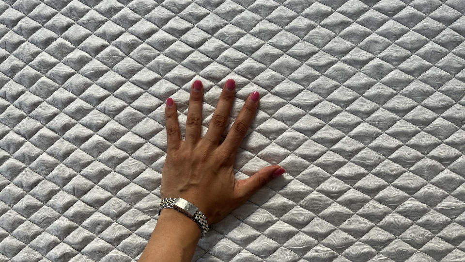 Reviewer's hand resting on cover of Leesa Sapira mattress