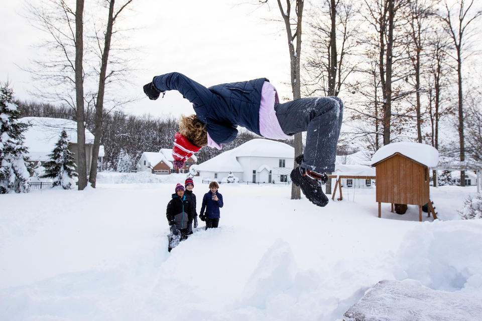 Gavin Reashor does a backflip into the snow while his friends look on during a break in the snowstorm hitting the Buffalo area, in Orchard Park, New York, on Nov. 19, 2022.