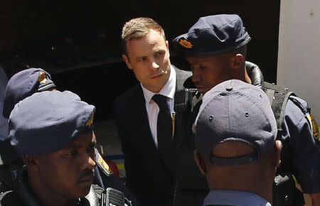 South African Olympic and Paralympic sprinter Oscar Pistorius (C) is escorted to a police van after his sentencing at the North Gauteng High Court in Pretoria October 21, 2014. REUTERS/Siphiwe Sibeko