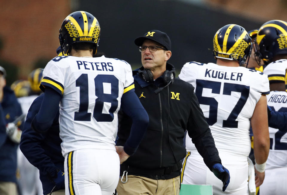 Michigan head coach Jim Harbaugh, center, speaks with quarterback Brandon Peters in the first half of an NCAA college football game against Maryland in College Park, Md., Saturday, Nov. 11, 2017. (AP Photo/Patrick Semansky)