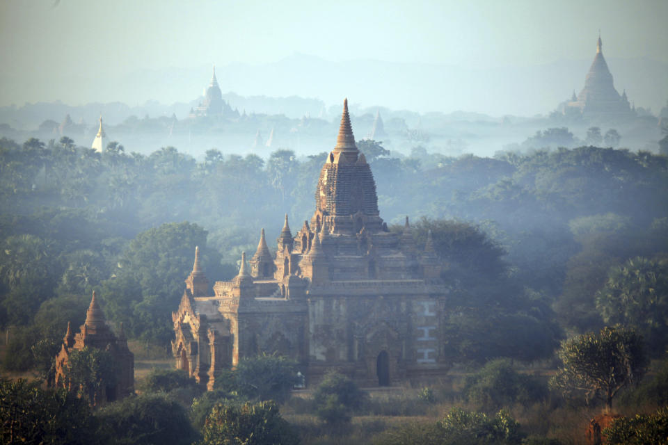 In this Aug. 15, 2013 photo, ancient temples stand at sunrise in Bagan, central Myanmar. After closing its doors to the West for half a century, Myanmar has reopened, inviting all to come and discover its treasures, ancient palaces of kings long gone, legends and mysteries told in stone. With ill-equipped roads and railways, there is no better way to explore than by river. Public ferries crisscross through glistening green paddies; old teak fishing boats can be rented by the day. (AP Photo/Khin Maung Win)