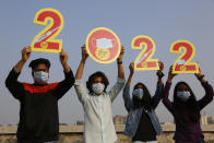 Indians, wearing face masks to help curb the spread of the coronavirus, hold the cutouts to welcome 2022 on New Year’s Eve in Ahmedabad, India, Friday, Dec. 31, 2021. (AP Photo/Ajit Solanki)