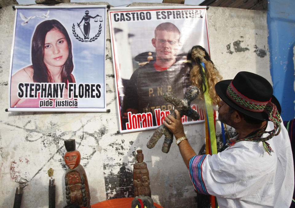 FILE - A shaman spits flowered water as he performs a ritual in front of posters of Stephany Flores, left, and Joran van der Sloot outside San Pedro prison where Van der Sloot's trial will start in connection with her murder in the Lurigancho area of Lima, Peru, Jan. 6, 2012. The poster of Flores reads in Spanish "Stephany Flores asks for justice" and the poster of Van der Sloot reads "Spiritual punishment." In 2012, Van der Sloot was sentenced to 28 years in prison for the Flores killing. (AP Photo/Karel Navarro, File)