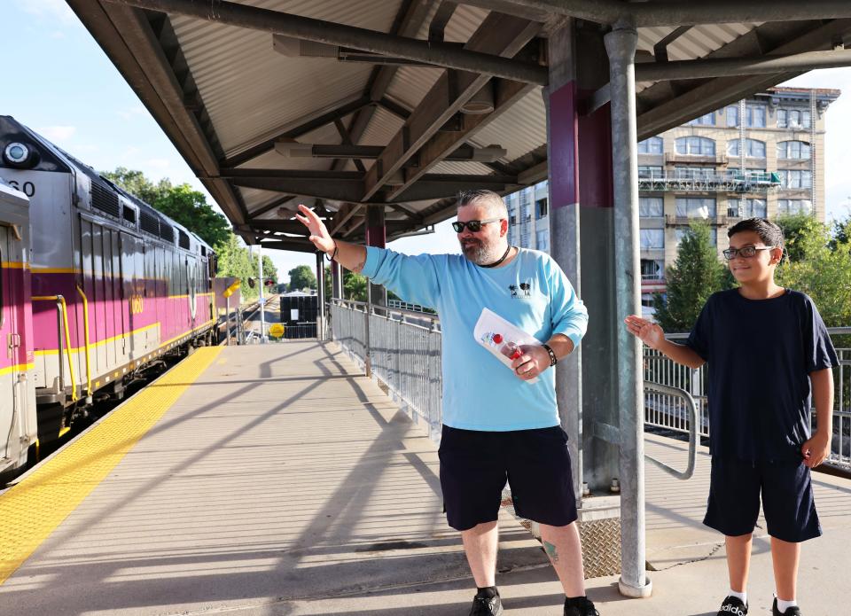 From left, Matt Stanton, and Dominic Gonzalez, 12,  wave goodbye to passengers on the Cape Cod Flyer at the Brockton stop on Friday, Aug. 12, 2022.