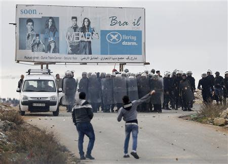 Palestinian policemen hold shields as demonstrators throw stones outside the Jalazoun refugee camp near the West Bank city of Ramallah January 12, 2014. REUTERS/Mohamad Torokman