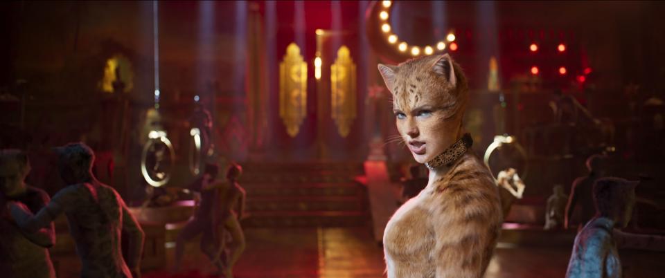 Taylor Swift as Bombalurina in a scene from the film "Cats," wearing feline makeup and costume, set in a theatrical, dimly lit venue
