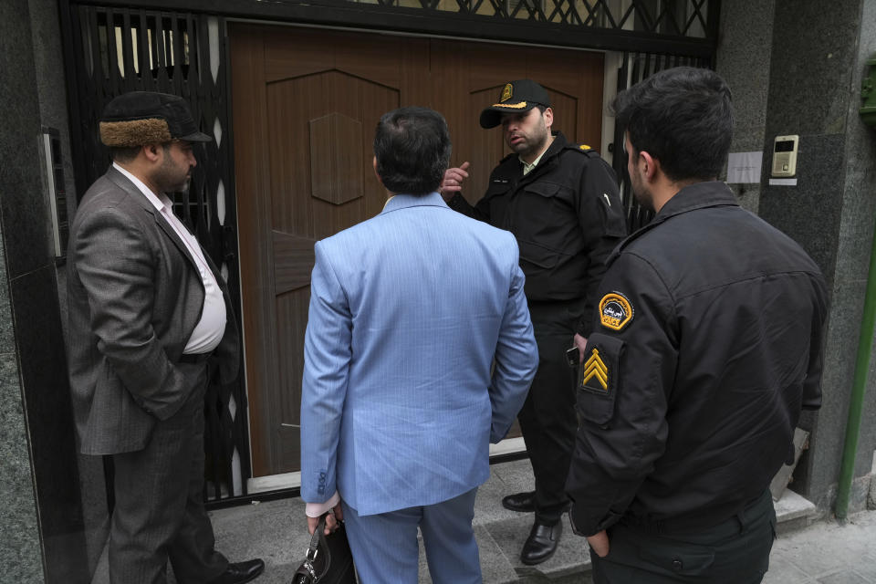 An Iranian police officer talks with a judiciary official in front of the door of the building of the Azerbaijan Embassy in Tehran, Iran, Friday, Jan. 27, 2023. A man armed with a Kalashnikov-style rifle stormed the Azerbaijan Embassy in Iran's capital Friday, killing the head of security at the diplomatic post and wounding two guards, authorities said. (AP Photo/Vahid Salemi)