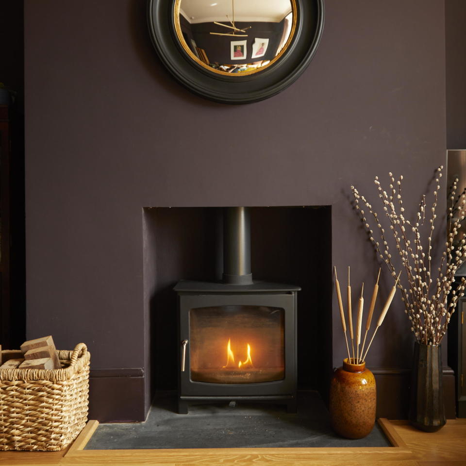 Chimney breast painted chocolate brown wall with wood burning stove framed by natural accessories