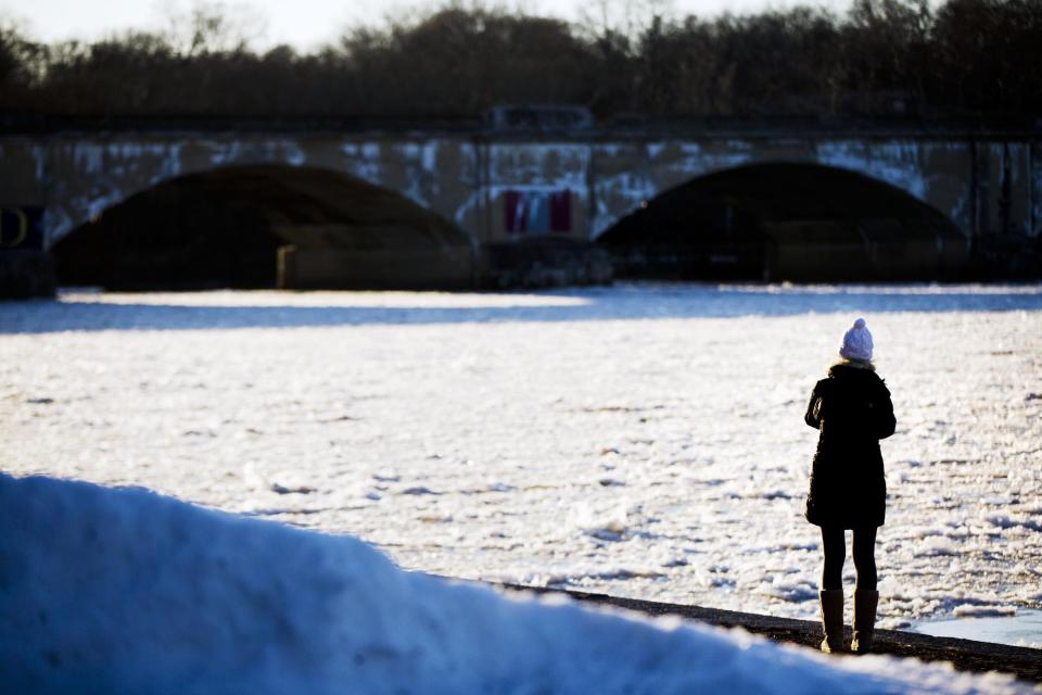 A woman pauses to see the Schuylkill River covered with ice, Tuesday, Jan. 7, 2014, in Philadelphia. Philadelphia experienced low temperatures hovering around zero and wind chills in the minus-teens. (AP Photo/Matt Rourke)