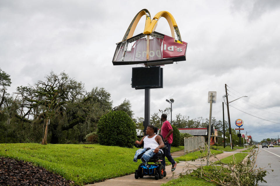 People pass by a damaged McDonald's sign.