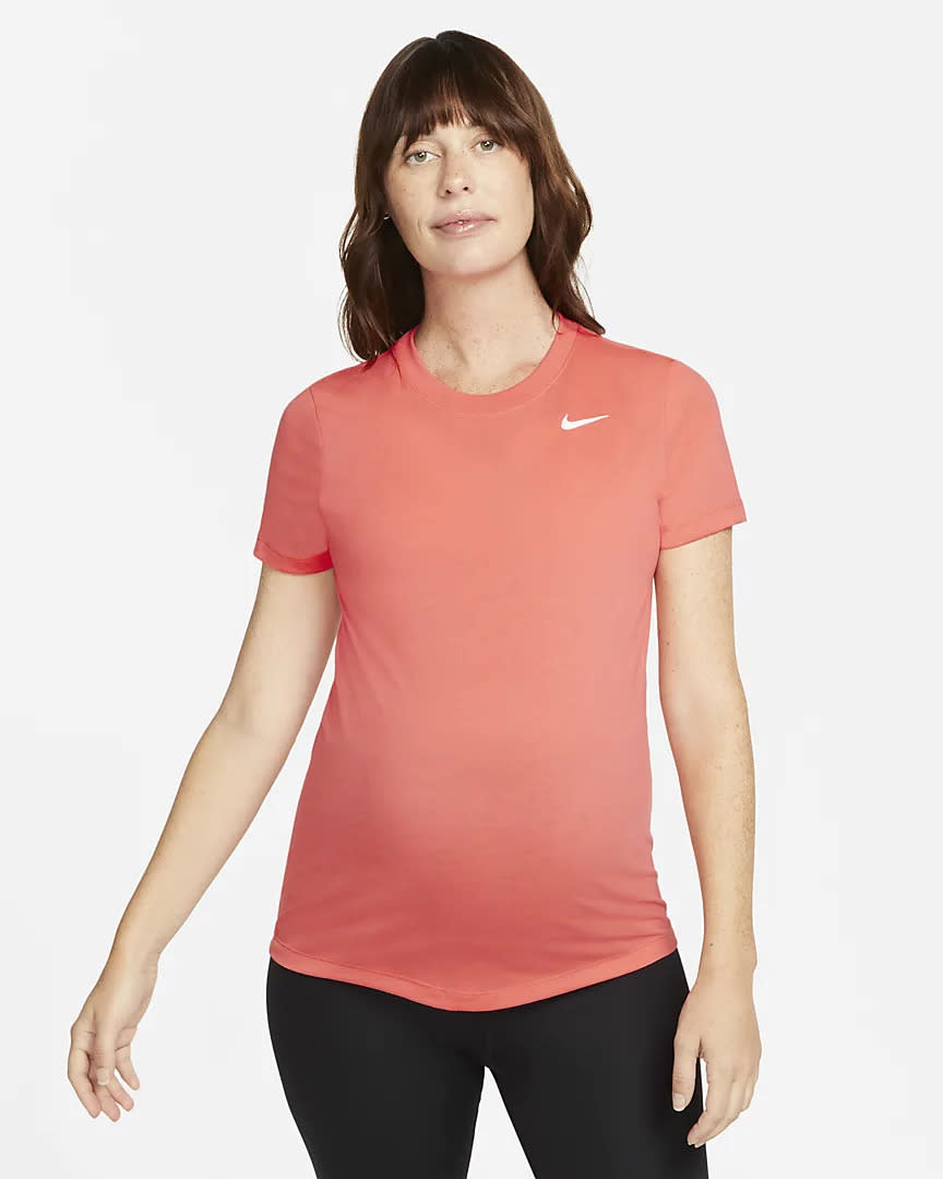 Woman wearing a coral Nike maternity shirt.