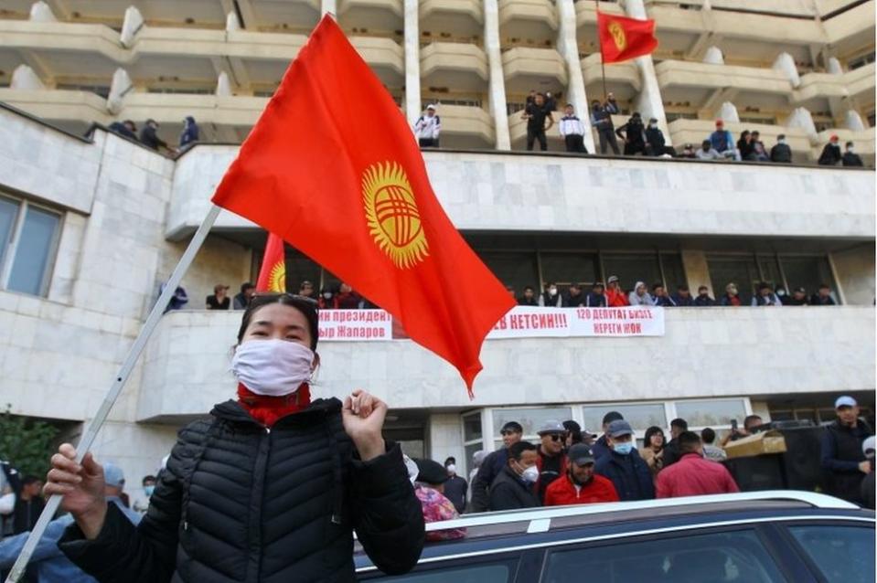 A woman holds the national flag as supporters of Kyrgyzstan"s Prime Minister Sadyr Japarov attend a rally in Bishkek, Kyrgyzstan October 15, 2020.