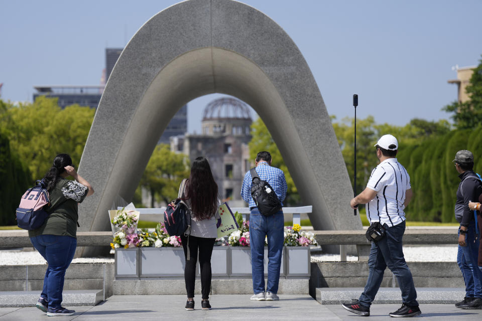 Visitors pray before flowers placed at the Hiroshima Peace Memorial Park, ahead of the Group of Seven nations' meetings in Hiroshima, western Japan, Wednesday, May 17, 2023. The G-7 summit starts Friday. (AP Photo/Hiro Komae)