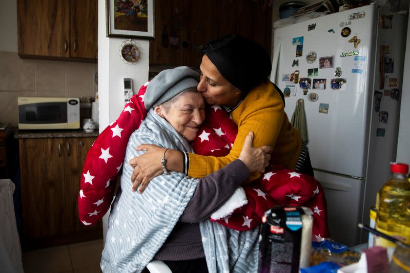 Tchuva Kabra, from Chasdei Naomi, a non-profit organisation that provides help to thousands of Holocaust survivors in Israel, hugs Holocaust survivor Maya Shulman, 88, after giving her a donation of food and a warm winter blanket, in Beit Shemesh, Israel