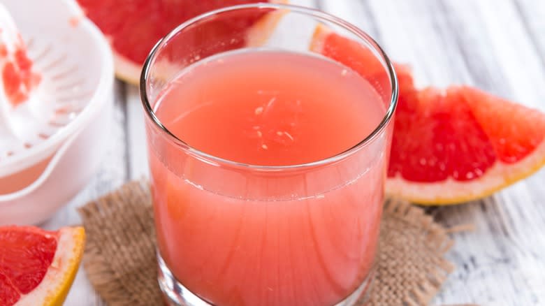 A glass of grapefruit juice next to grapefruit slices