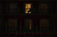 A woman sits on the balcony of her home on the Mayor square in downtown Madrid, Spain, Friday, Oct. 23, 2020. In much of Europe, city squares and streets, be they wide, elegant boulevards like in Paris or cobblestoned alleys in Rome, serve as animated evening extensions of drawing rooms and living rooms. As Coronavirus restrictions once again put limitations on how we live and socialize, AP photographers across Europe delivered a snapshot of how Friday evening, the gateway to the weekend, looks and feels. (AP Photo/Manu Fernandez)