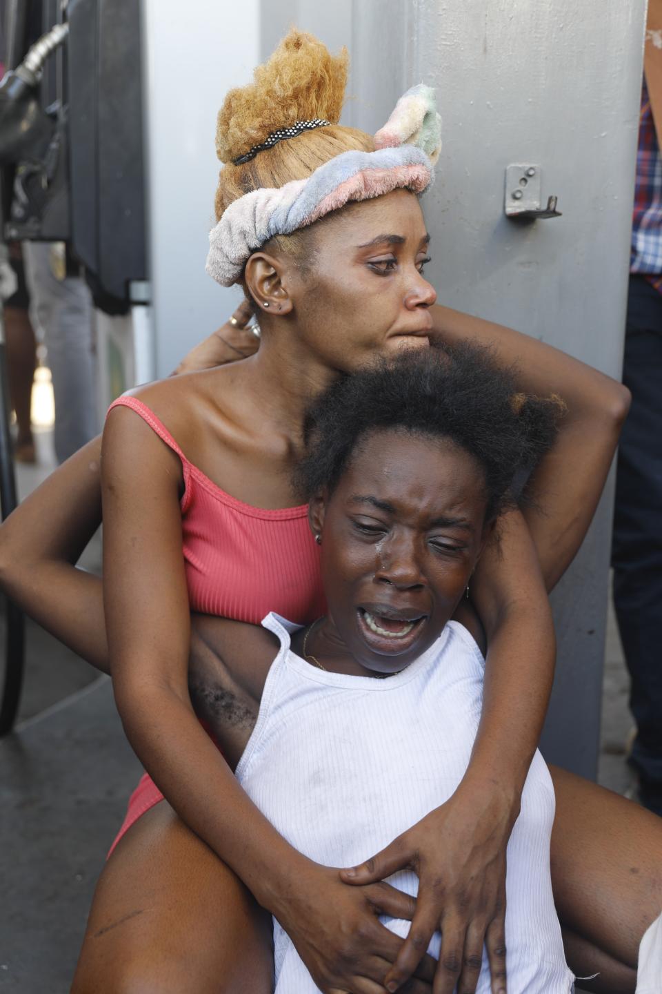 The relative, below, of a person found dead in the street reacts after an overnight shooting in the Petion Ville neighborhood of Port-au-Prince, Haiti, Monday, March 18, 2024. (AP Photo/Odelyn Joseph)