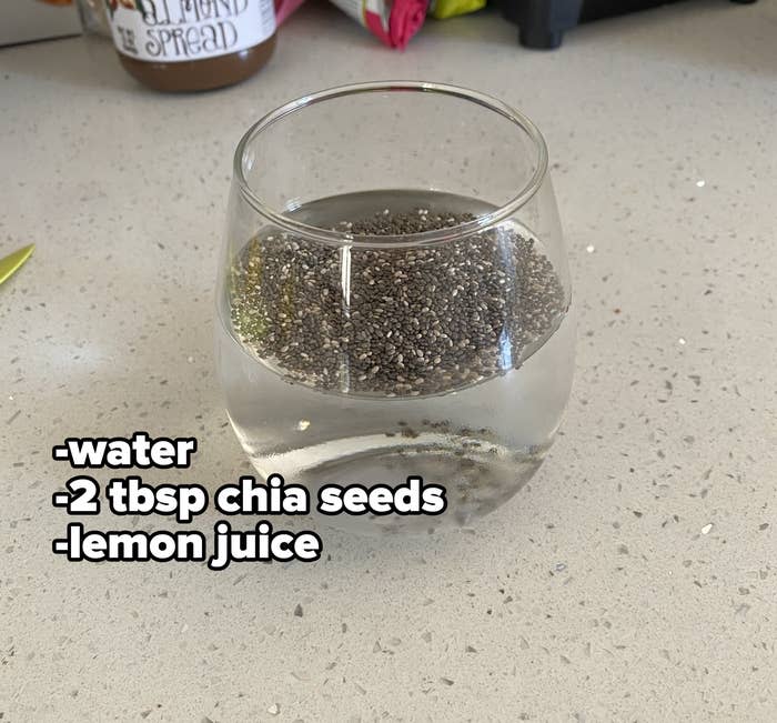 A glass that's half full of water with chia seeds floating on top