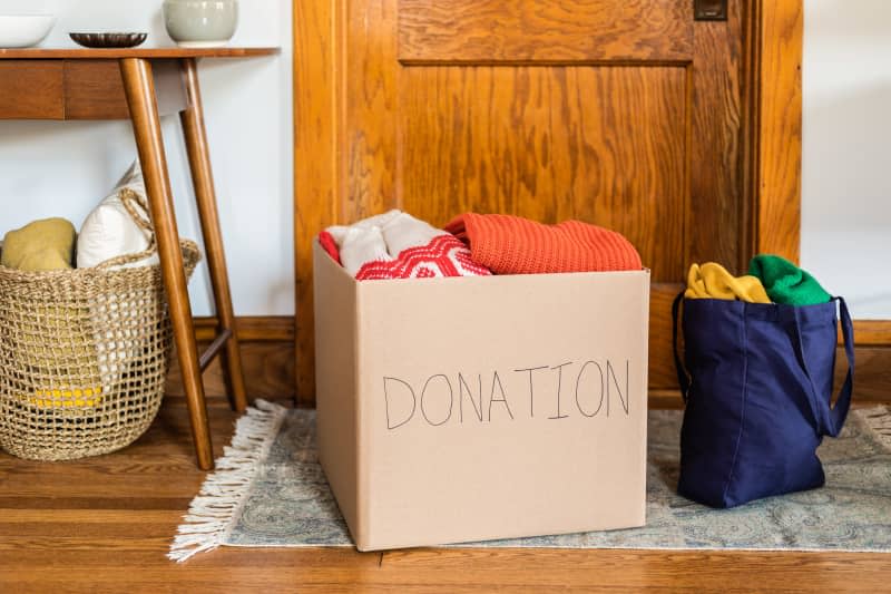 donation box full of clothes next to tote bag