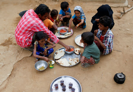 Afaf Hussein, 10, who is malnourished, eats a tin of peas provided for her recovery as her father Hussein Abdu, 40, and other relatives and friends have a meal outside their house in the village of al-Jaraib, in the northwestern province of Hajjah, Yemen, February 19, 2019. REUTERS/Khaled Abdullah