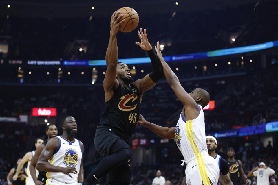 Cleveland Cavaliers guard Donovan Mitchell, center, shoots between Golden State Warriors guard Chris Paul, right, and forward Draymond Green, left, during the first half of an NBA basketball game, Sunday, Nov. 5, 2023, in Cleveland. (AP Photo/Ron Schwane)