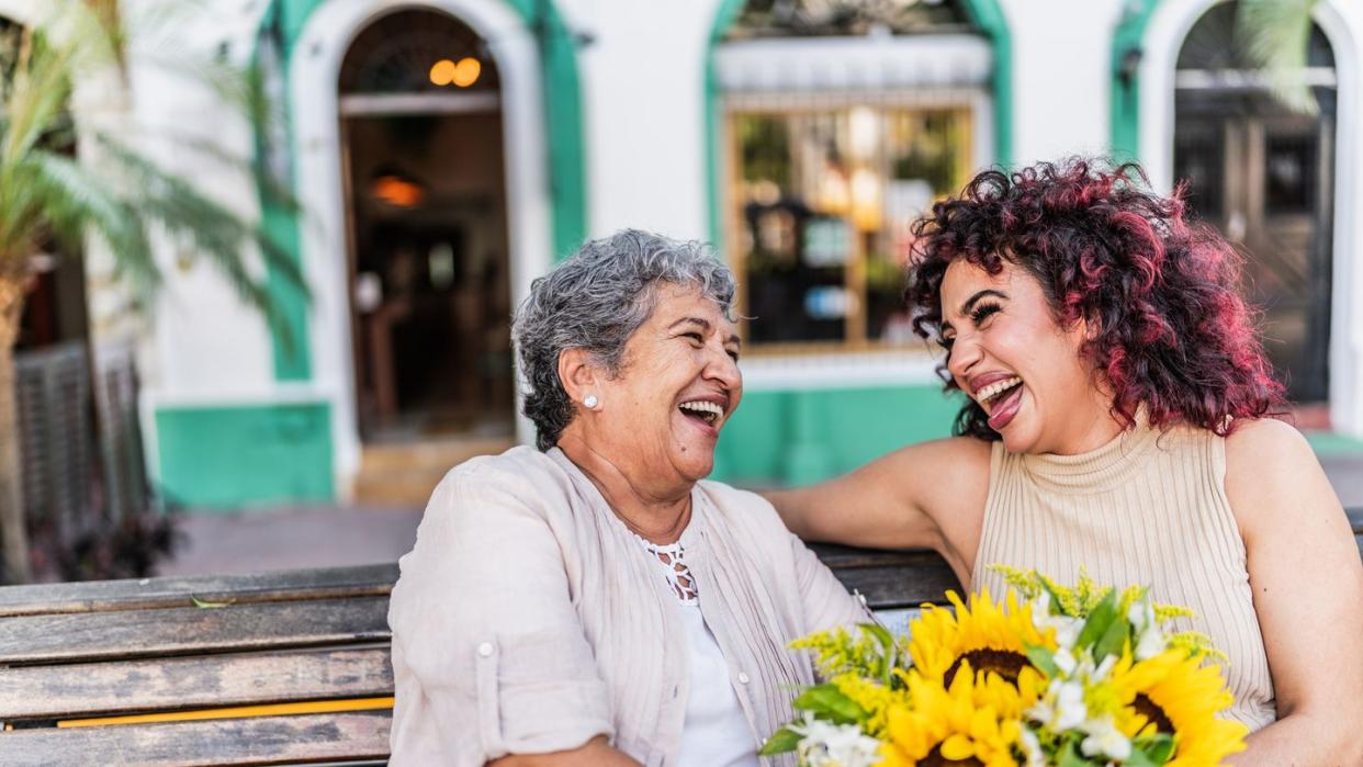 two women talking on bench with bouquet