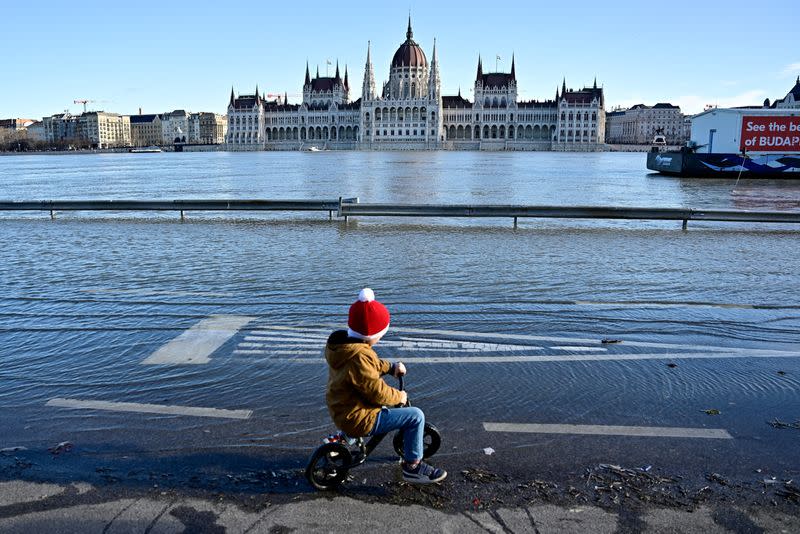 Un niño anda en bicicleta en un muelle inundado por el río Danubio en Budapest, Hungría