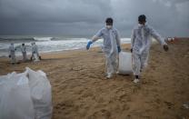 Sri Lankan navy soldiers carry sacks full of plastic debris washed ashore from fire damaged container ship MV X-Press Pearl at Kapungoda, on the outskirts of Colombo, Sri Lanka. Monday, June 14, 2021. (AP Photo/Eranga Jayawardena)