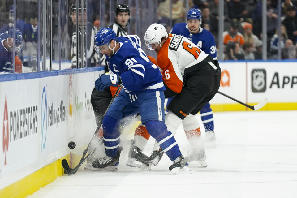 Toronto Maple Leafs center John Tavares (91) and Philadelphia Flyers defenseman Travis Sanheim (6) vie for the puck during the first period of an NHL hockey game Thursday, Feb. 15, 2024, in Toronto. (Arlyn McAdorey/The Canadian Press via AP)