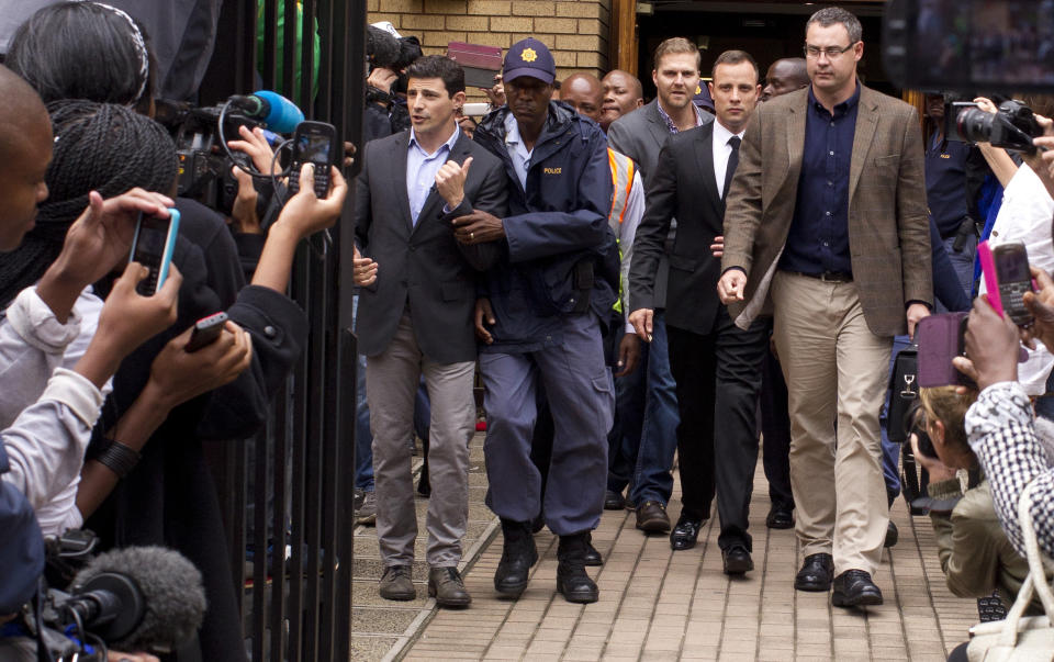 Oscar Pistorius, center, walks out of the high court in Pretoria, South Africa, Friday, March 14, 2014. Pistorius is charged with murder for the shooting death of his girlfriend, Reeva Steenkamp, on Valentines Day in 2013. (AP Photo/Themba Hadebe)