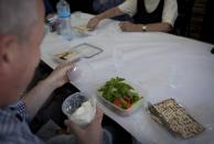 In this photo taken Wednesday, April 16, 2014, Israeli members of a group tour, who are observing religious tradition, pull out containers with matza, unleavened bread, to eat alongside plates of hummus and olives, as the trip fell in the week of the Jewish holiday of Passover, during a lunch at a local restaurant following their tour, that is organized by IPCRI, an Israeli Palestinian group promoting co-existence, in the West Bank city of Ramallah. This bustling center of Palestinian life is just a 20-minute drive from Jerusalem, but for Israelis it might as well be on the other side of the world. (AP Photo/Nasser Nasser)