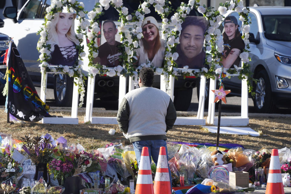 FILE - A person pauses to pay respects as portraits of the victims of a mass shooting at a gay nightclub are displayed at a makeshift memorial, Nov. 22, 2022, near the scene in Colorado Springs, Colo. (AP Photo/David Zalubowski, File)