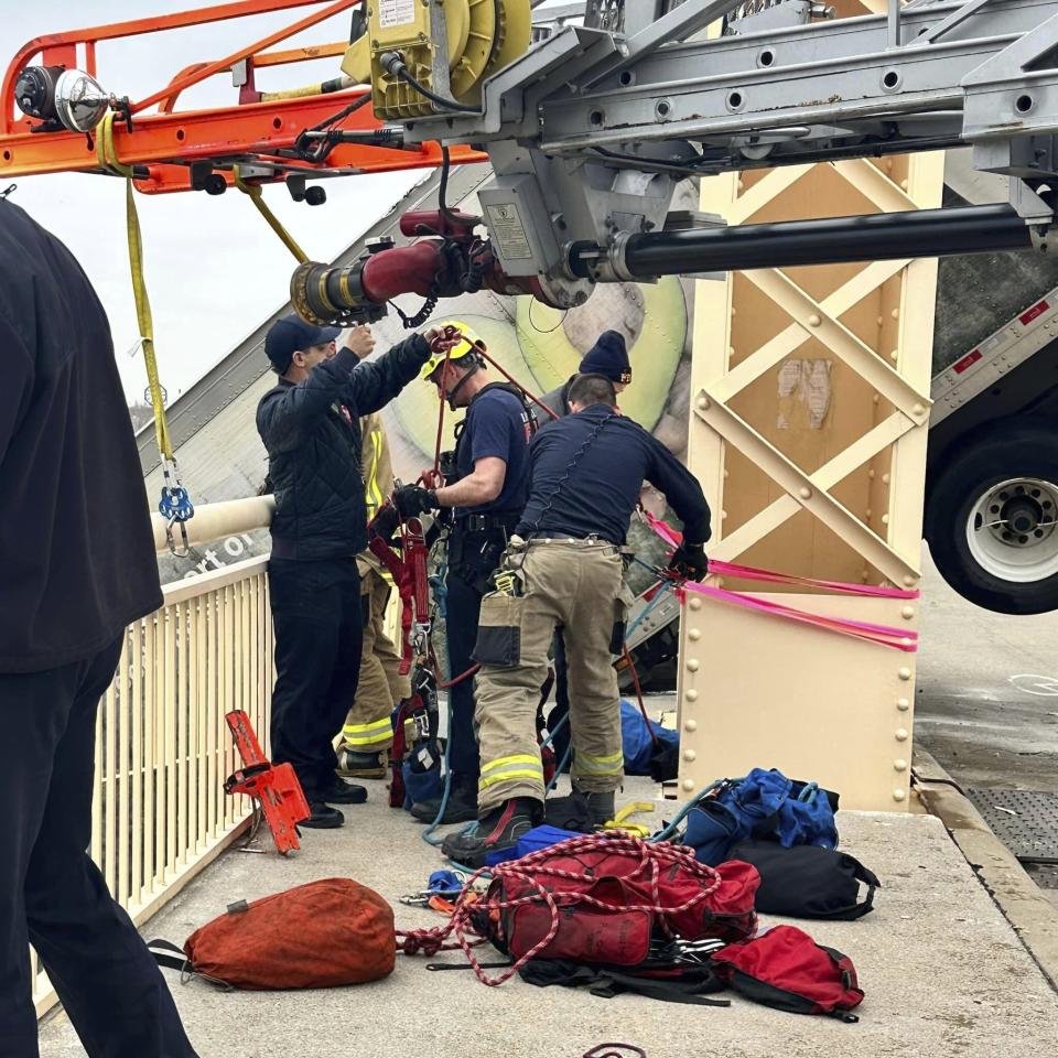 This photo provided by Louisville Division of Fire, Louisville Fire Dept. Louisville firefighter Bryce Carden prepares to rescue the driver of semitruck that is dangling off the Clark Memorial Bridge over the Ohio River on Friday, March 1, 2024 in Louisville, Ky. The driver was pulled to safety by firefighters following the three-vehicle crash on the bridge connecting Louisville, Kentucky to southern Indiana(Louisville Division of Fire via AP)