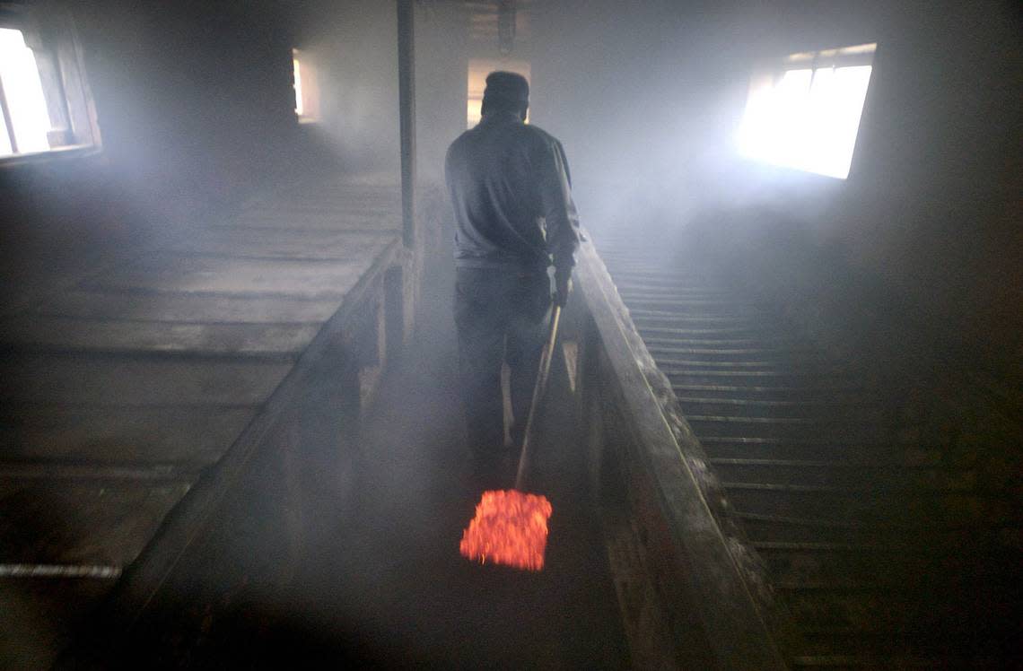 A shovel full of glowing hardwood coals are carried through the smoke-filled cookhouse at Wilber’s Barbecue in Goldsboro.