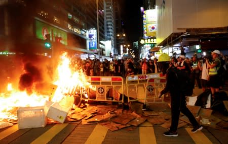 Protestors stand behind a burning barricade during a demonstration in Mong Kok district in Hong Kong