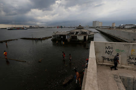 Youth play near a mosque by the sea wall in Muara Baru port in Jakarta, Indonesia, January 3, 2018. REUTERS/Beawiharta