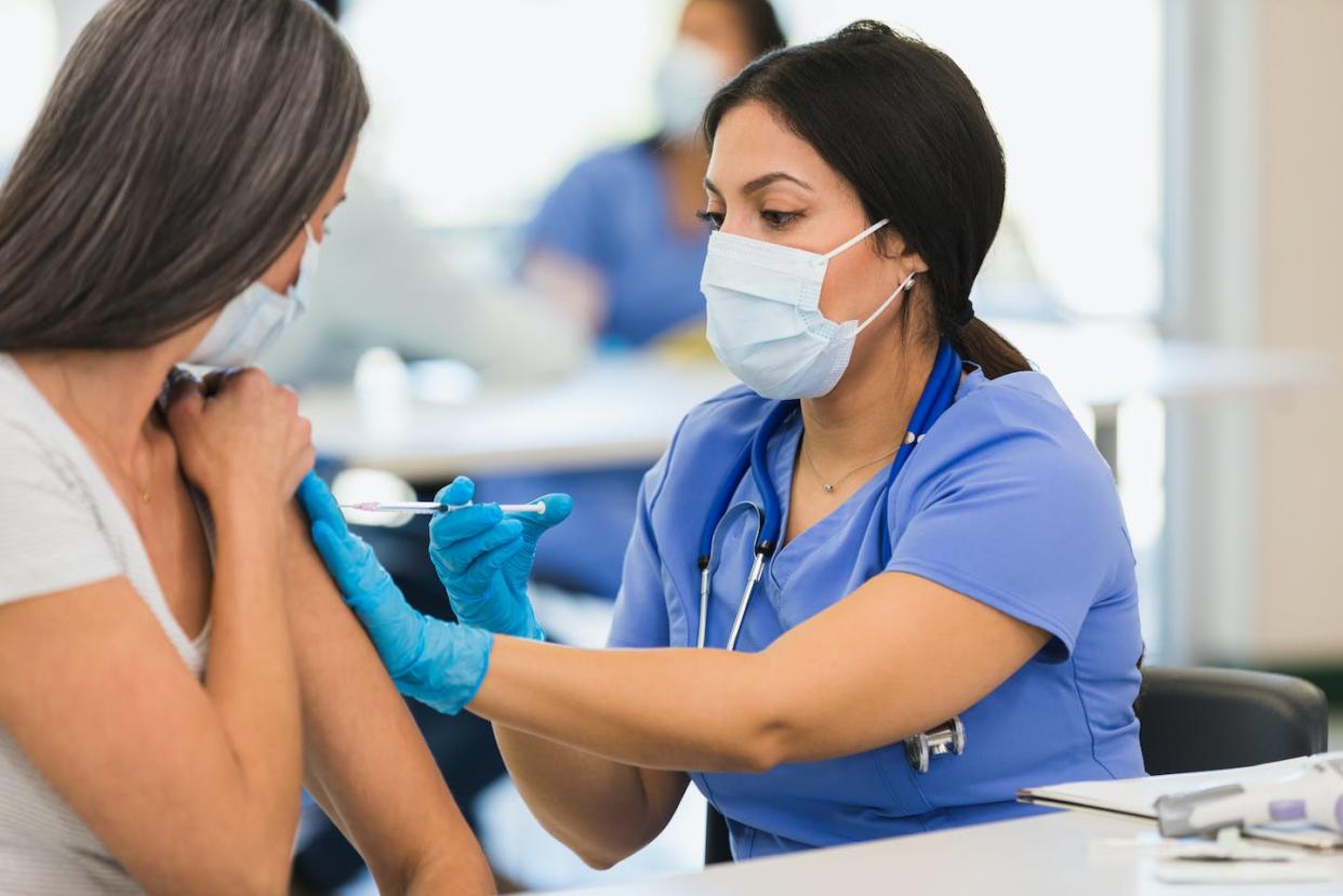It is safe to get the newly formulated COVID-19 booster shot and the flu shot at the same time. <a href="https://www.gettyimages.com/detail/photo/close-up-photo-female-nurse-giving-vaccine-to-woman-royalty-free-image/1361778753?adppopup=true" rel="nofollow noopener" target="_blank" data-ylk="slk:SDI Productions/ E+ via Getty Images;elm:context_link;itc:0;sec:content-canvas" class="link ">SDI Productions/ E+ via Getty Images</a>