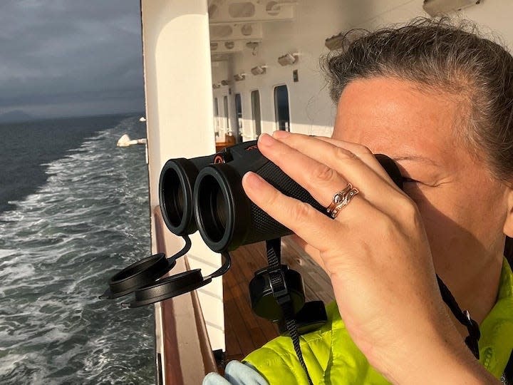 rebecca using binoculars to look off an alaskan cruise ship