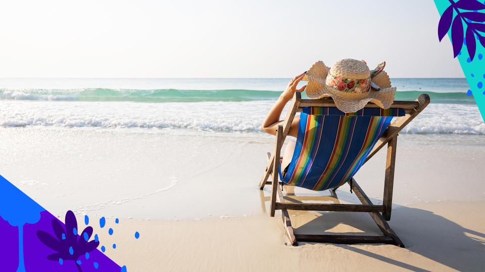 A behatted woman lounges in a colorful beach chair by the sea