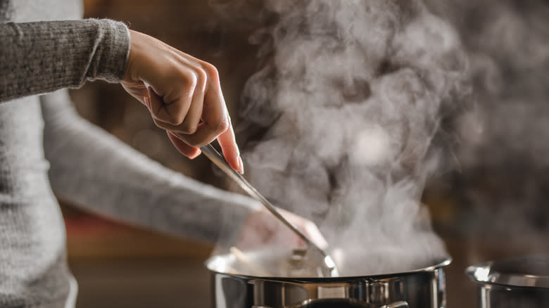 woman stirs a pot of boiling liquid