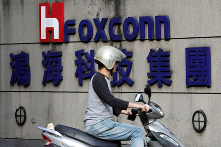 FILE PHOTO: A motorcyclist rides past the logo of Foxconn, the trading name of Hon Hai Precision Industry, in Taipei, Taiwan March 30, 2018. REUTERS/Tyrone Siu/File Photo