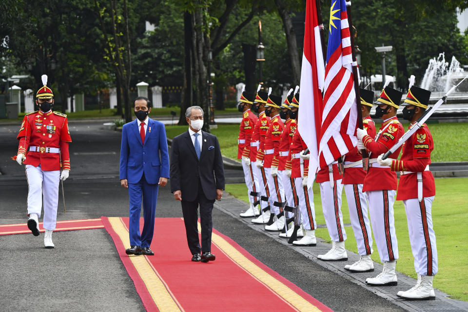In this photo released by Indonesian Presidential Palace, Malaysian Prime Minister Muhyiddin Yassin, center, walks with Indonesian President Joko Widodo as they inspect honor guards during their meeting at Merdeka Palace in Jakarta, Indonesia, Friday, Feb. 5, 2021. Yassin is currently on a two-day visit in the country. (Agus Suparto, Indonesian President Palace via AP)