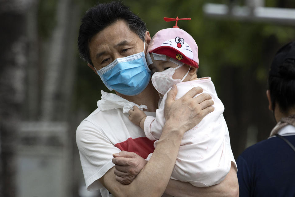 A man holds a child wearing masks to curb the spread of the coronavirus in Beijing on June 17. Source: AP