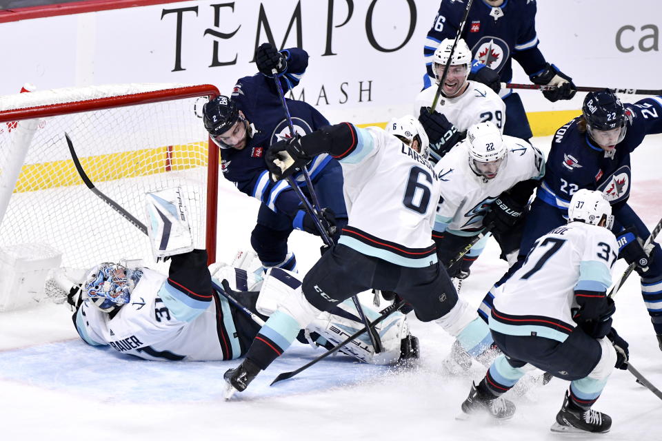 Seattle Kraken goaltender Philipp Grubauer (31) is knocked over by Winnipeg Jets' Dylan Demelo (2) during the first period of an NHL game in Winnipeg, Manitoba on Tuesday Feb. 14, 2023. (Fred Greenslade/The Canadian Press via AP)