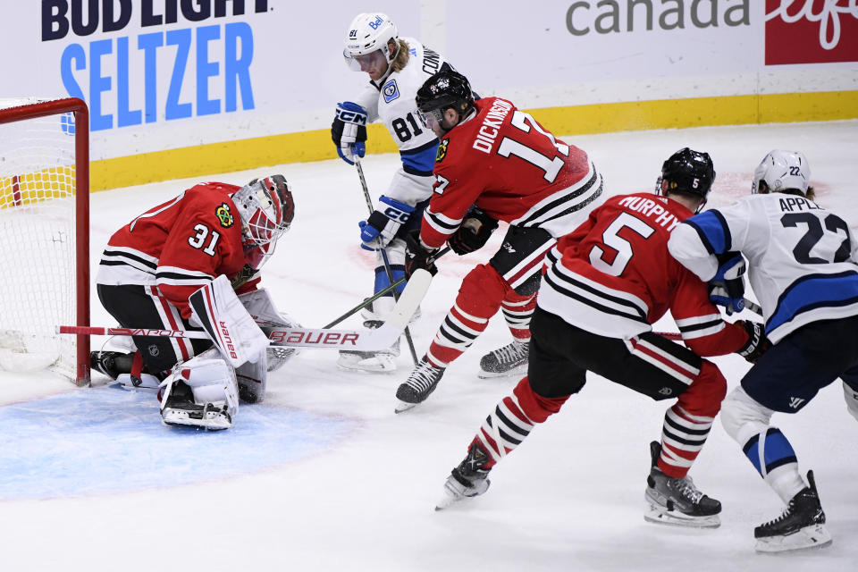 Chicago Blackhawks goaltender Dylan Wells makes a save on Winnipeg Jets' Kyle Connor (81) as Jason Dickinson (17) defends during the third period of an NHL hockey game in Winnipeg, Manitoba, Saturday, Nov. 5, 2022. (Fred Greenslade/The Canadian Press via AP)