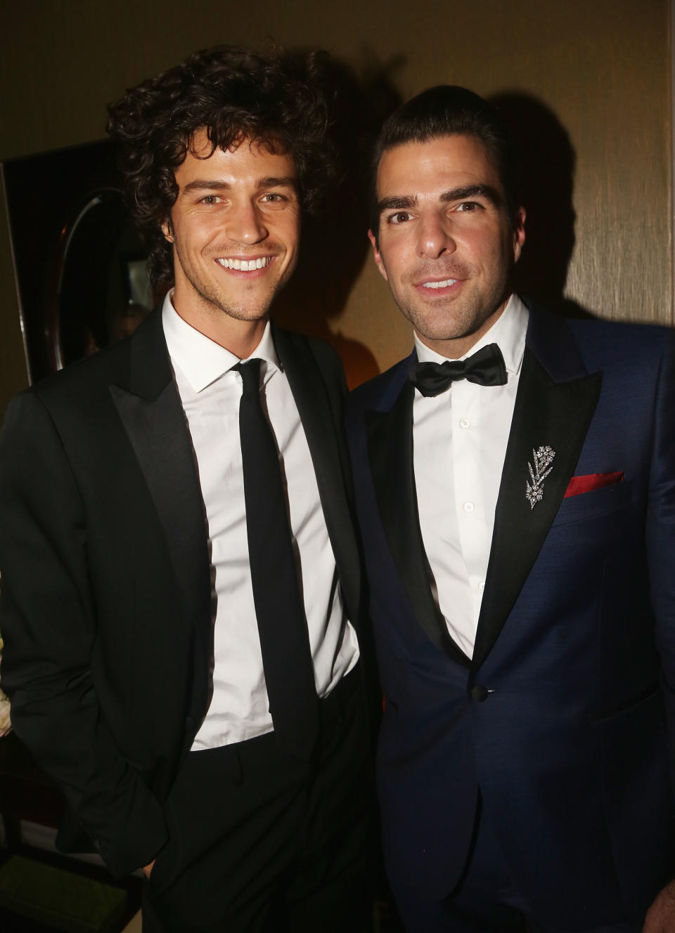 Two smiling men in formal suits, one in black tie and the other in a bow tie with handkerchief