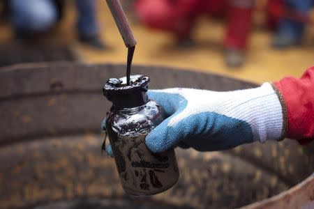 A worker collects crude oil sample at an oil well operated by Venezuela's state oil company PDVSA in Morichal July 28, 2011. REUTERS/Carlos Garcia Rawlins