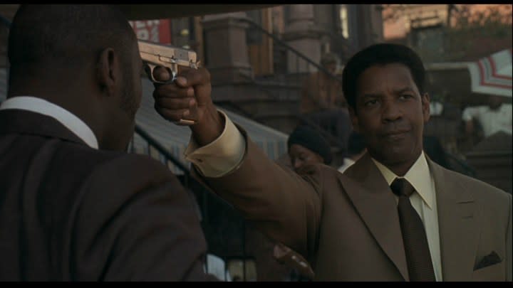 Denzel Washington holds a gun in American Gangster.