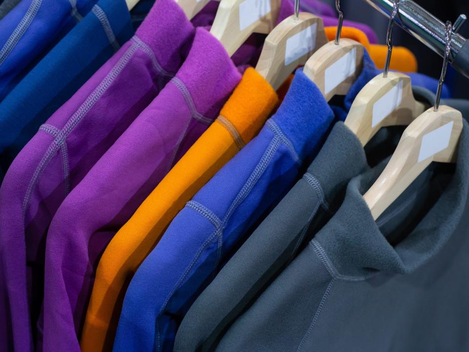 A rack of different colored fleeces on hangers